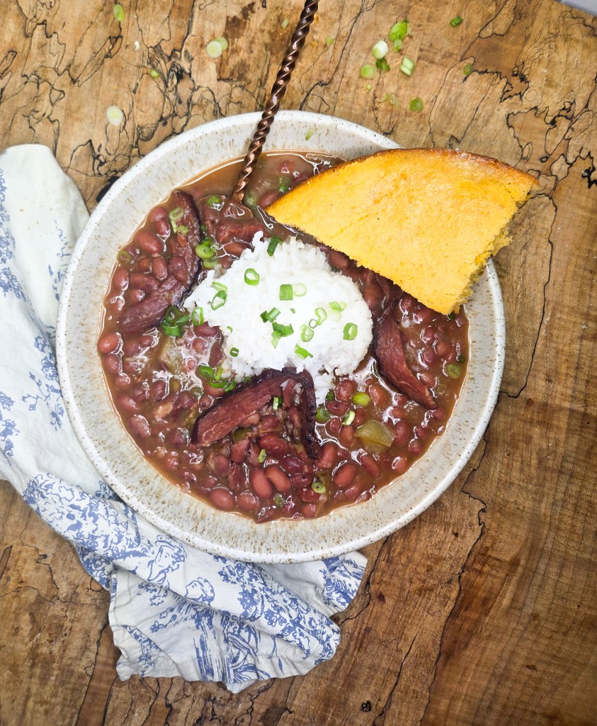 Red Beans and Rice is a slow cooked classic made with leftover ham bone, the holy trinity and signature spices served over white rice.