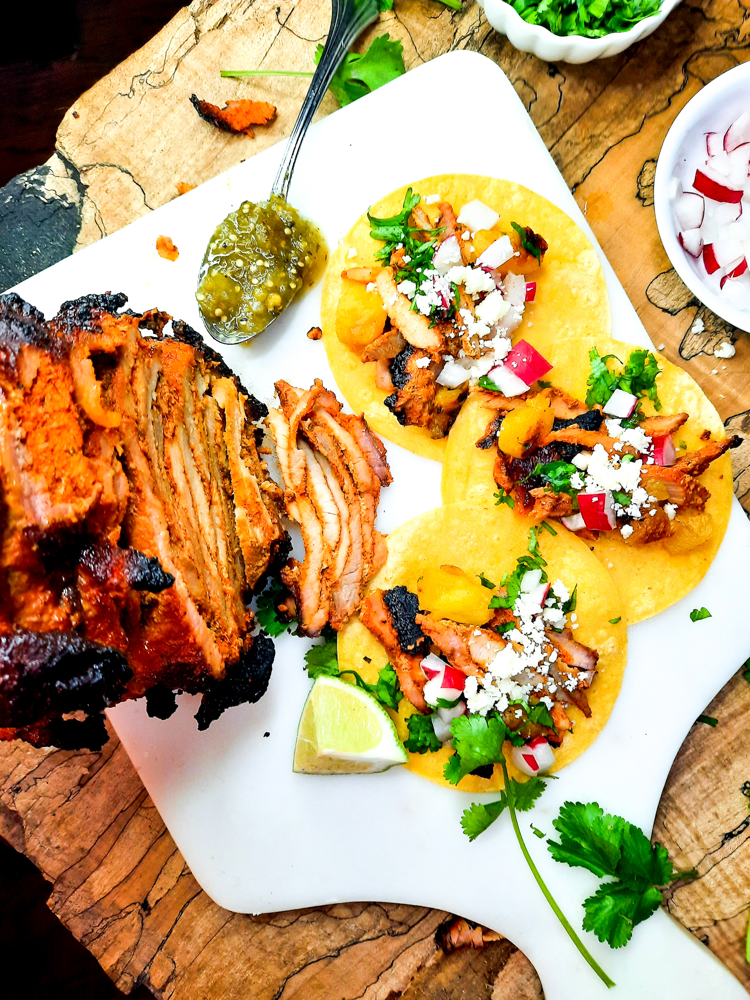 Cantina style Tacos al Pastor are marinated, grilled on the rotisserie and shaved off into your corn tortilla with bits of charred pineapple.