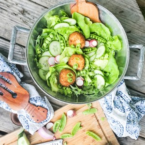 Lightly fried goat cheese medallions sit ever so delicately on this inviting summer salad with fresh, seasonal greens layered with cucumber, radish and garden peas.