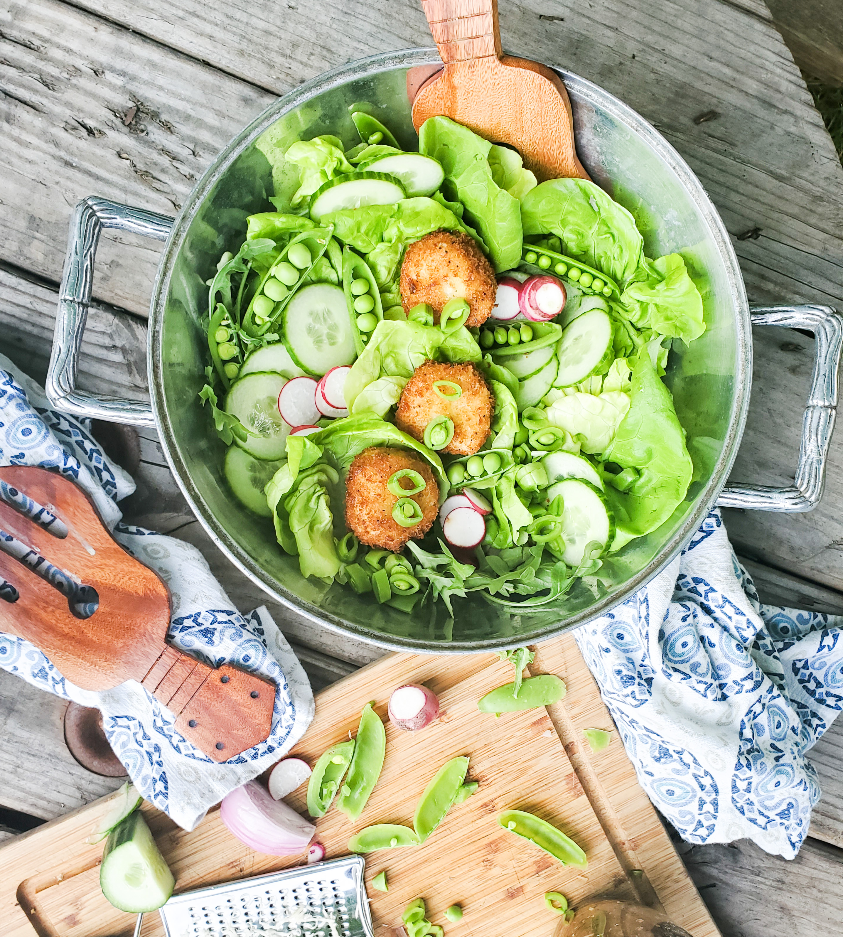 Lightly fried goat cheese medallions sit ever so delicately on this inviting summer salad with fresh, seasonal greens layered with cucumber, radish and garden peas.