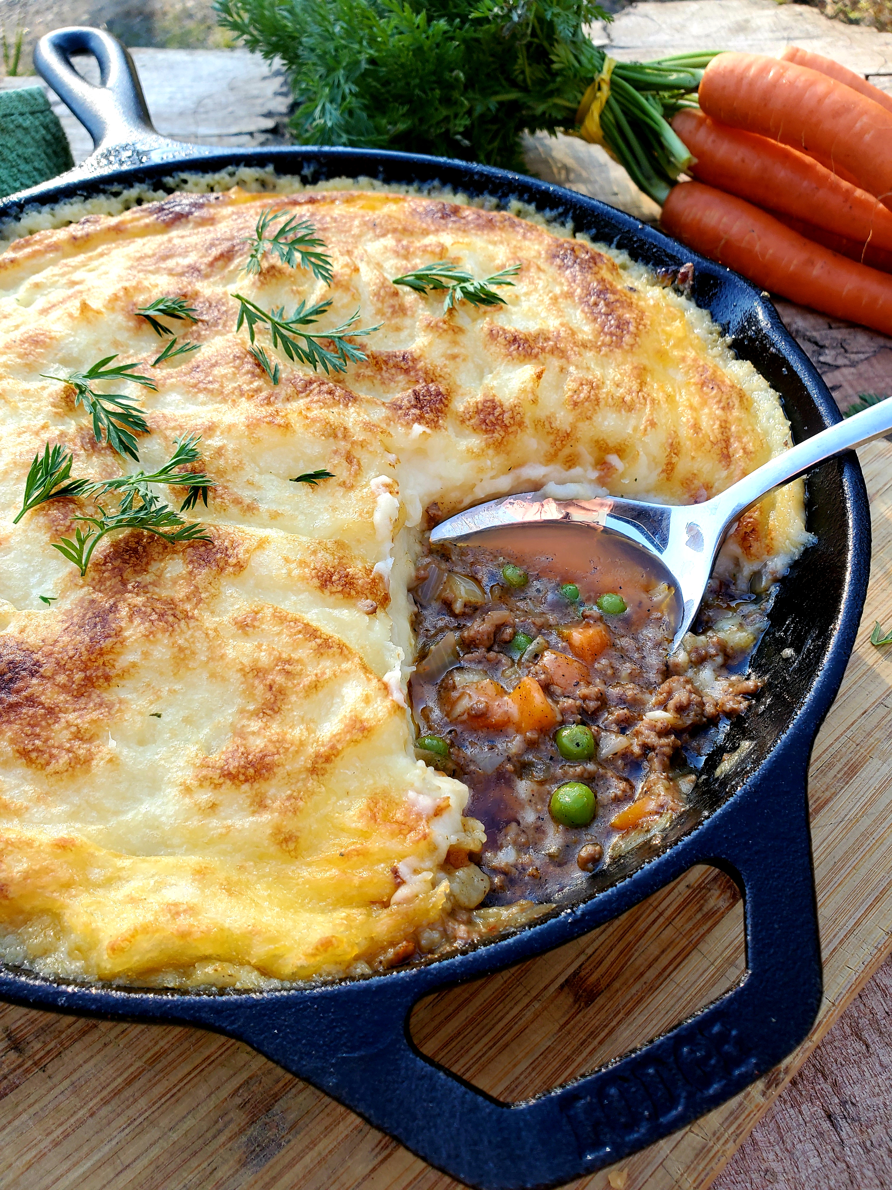 Classic Cottage Pie is made with spiced ground beef, tender carrots and peas. Topped with creamy potato cheese mixture and carrot tops.