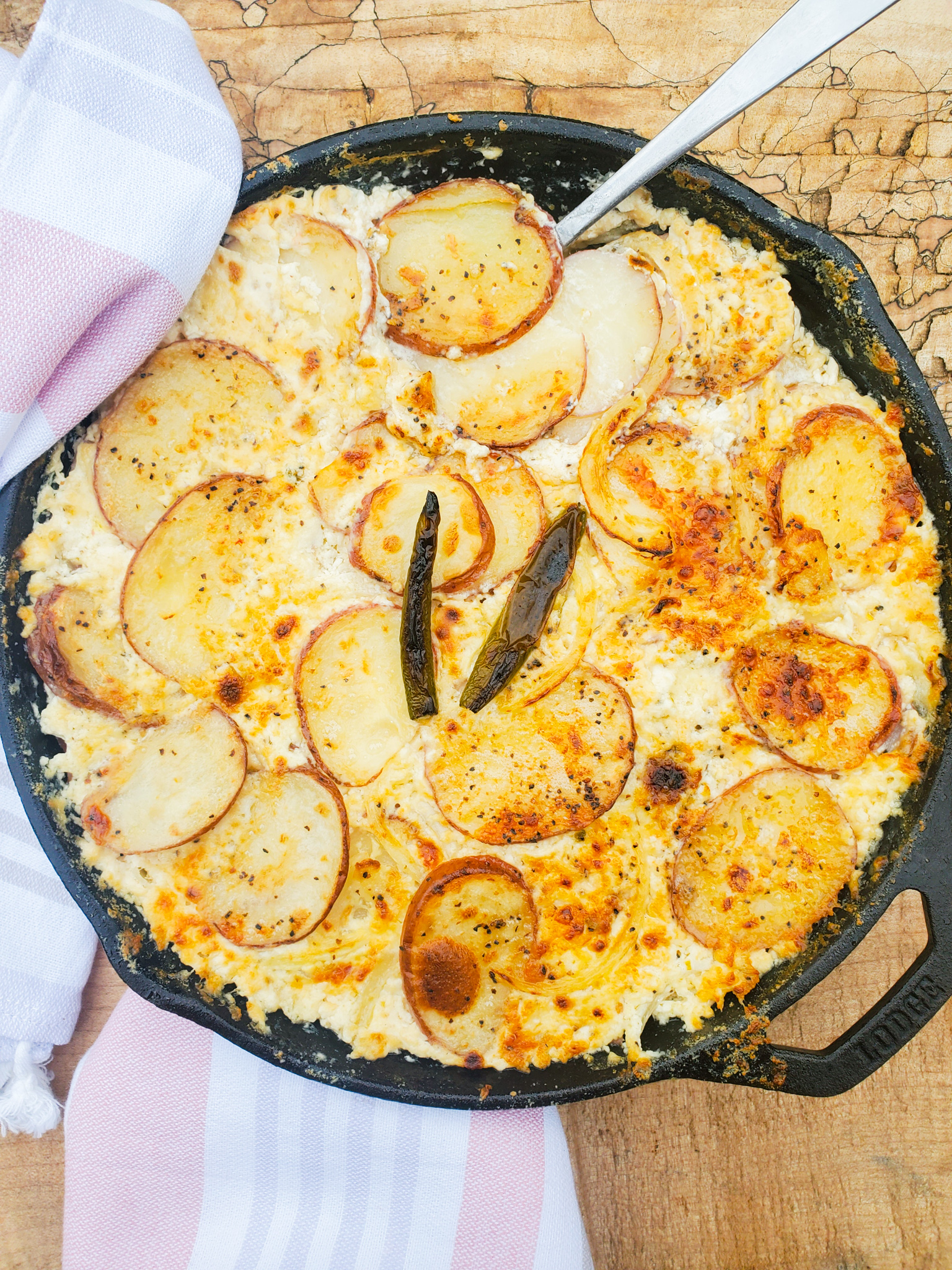 Golden browned red potato gratin with warm and spicy Serrano peppers