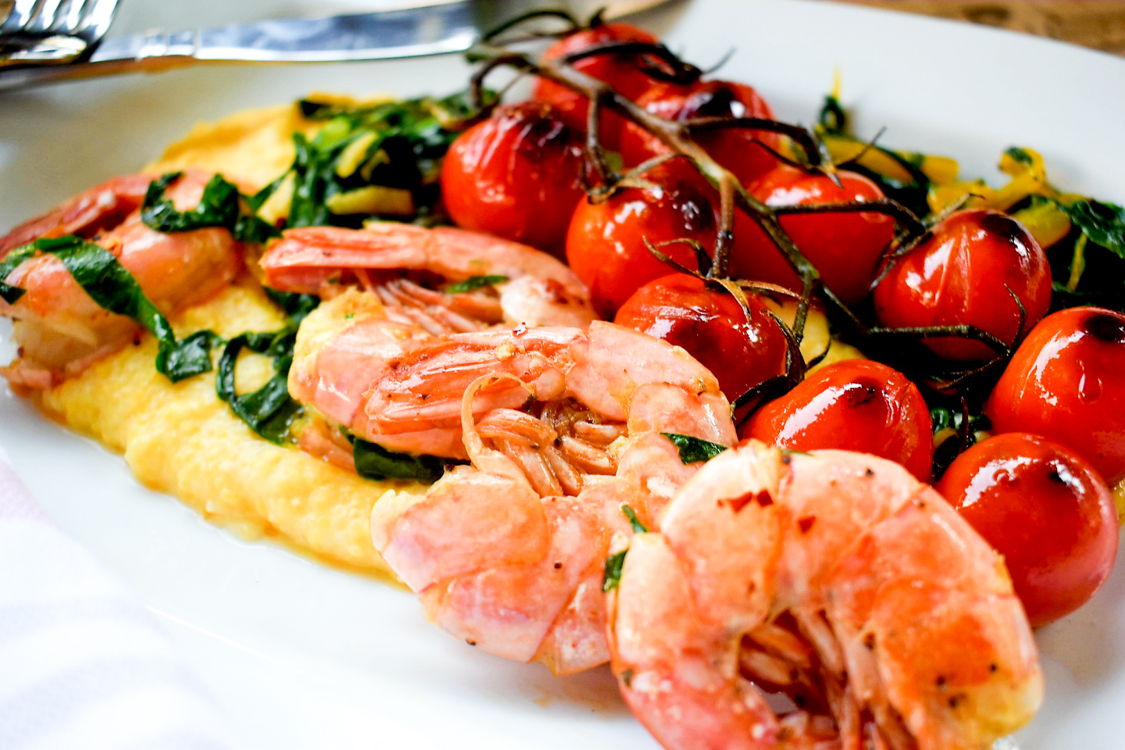 Garlic prawns with blistered tomatoes and Swiss chard over creamy polenta