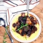 Red Wine Braised Short Ribs are first seared then cooked low and slow until fork tender with tender mushrooms and herbs in a pool of polenta.