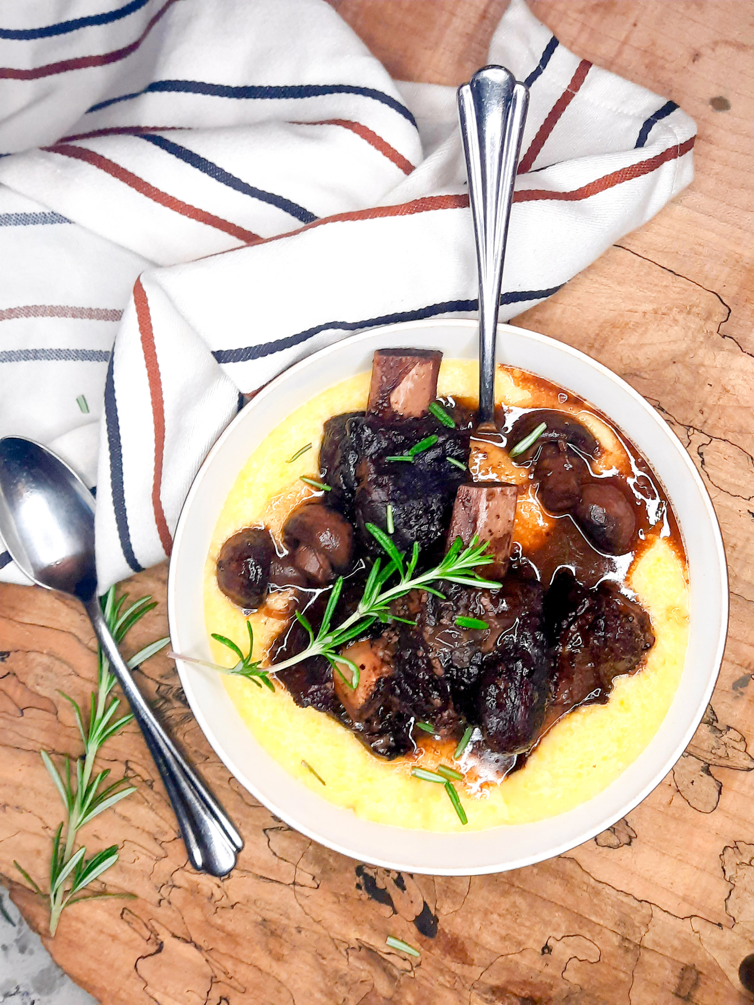 Red Wine Braised Short Ribs are first seared then cooked low and slow until fork tender with tender mushrooms and herbs in a pool of polenta.