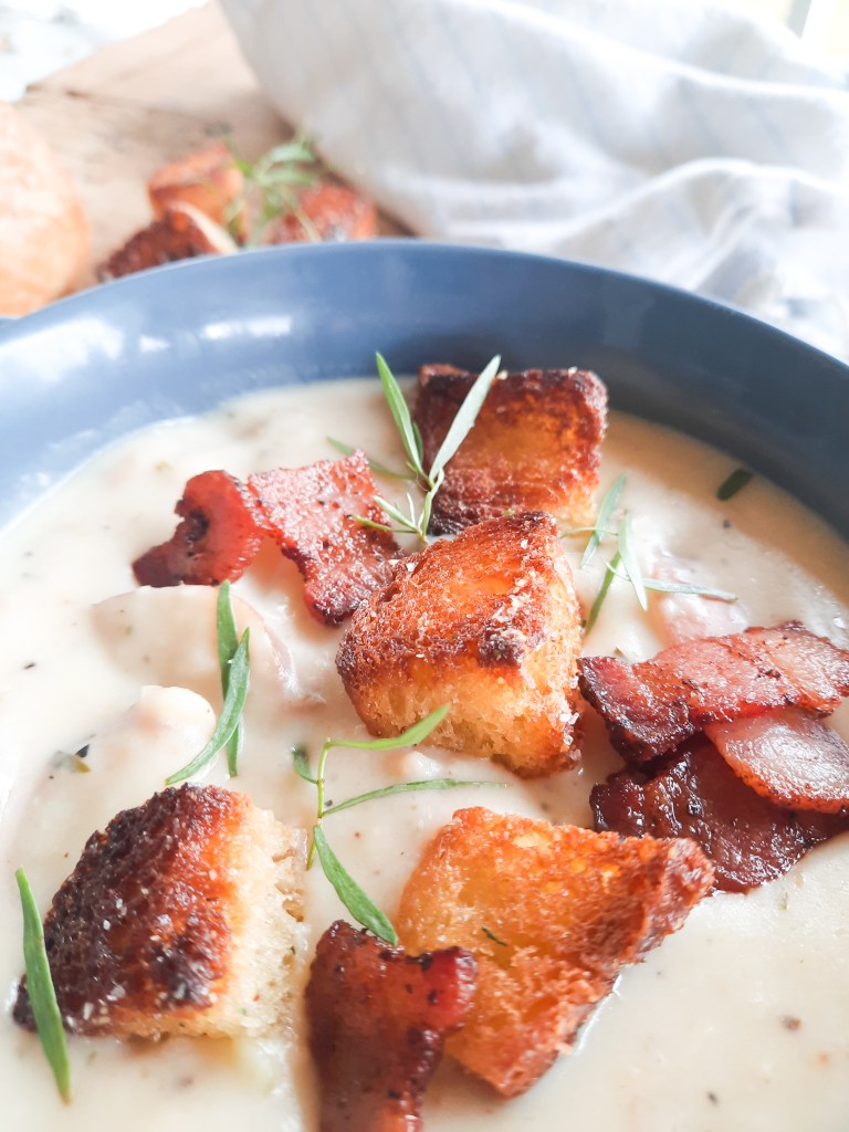 Classic, creamy Out West Clam Chowder with canned clams, red potatoes, celery, onion and tarragon, topped with bacon and homemade croutons.