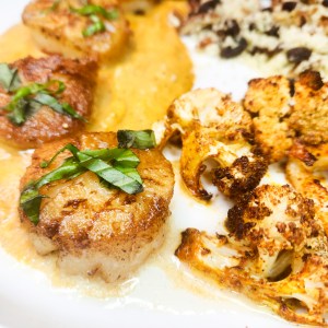 Indian Spiced Sea Scallops features garam masala infused butternut squash puree, roasted cauliflower and couscous with pecans and raisins.