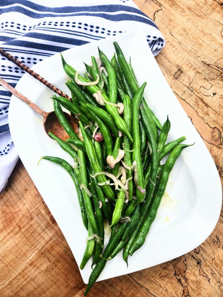 Shallot Citrus Green Beans served cold after being quickly marinated in a light agave lime dressing with shaved shallots.
