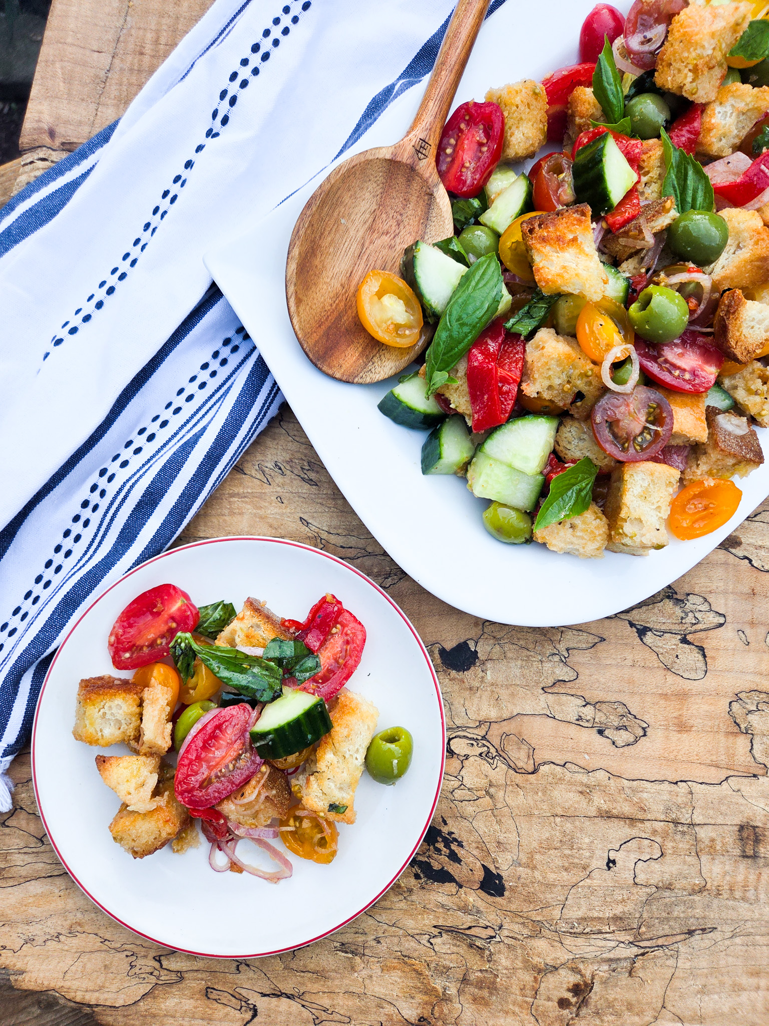 Panzanella Salad is simple and fresh with vine ripened tomatoes, olives, cucumber, peppers, basil, rustic bread and red wine vinaigrette.