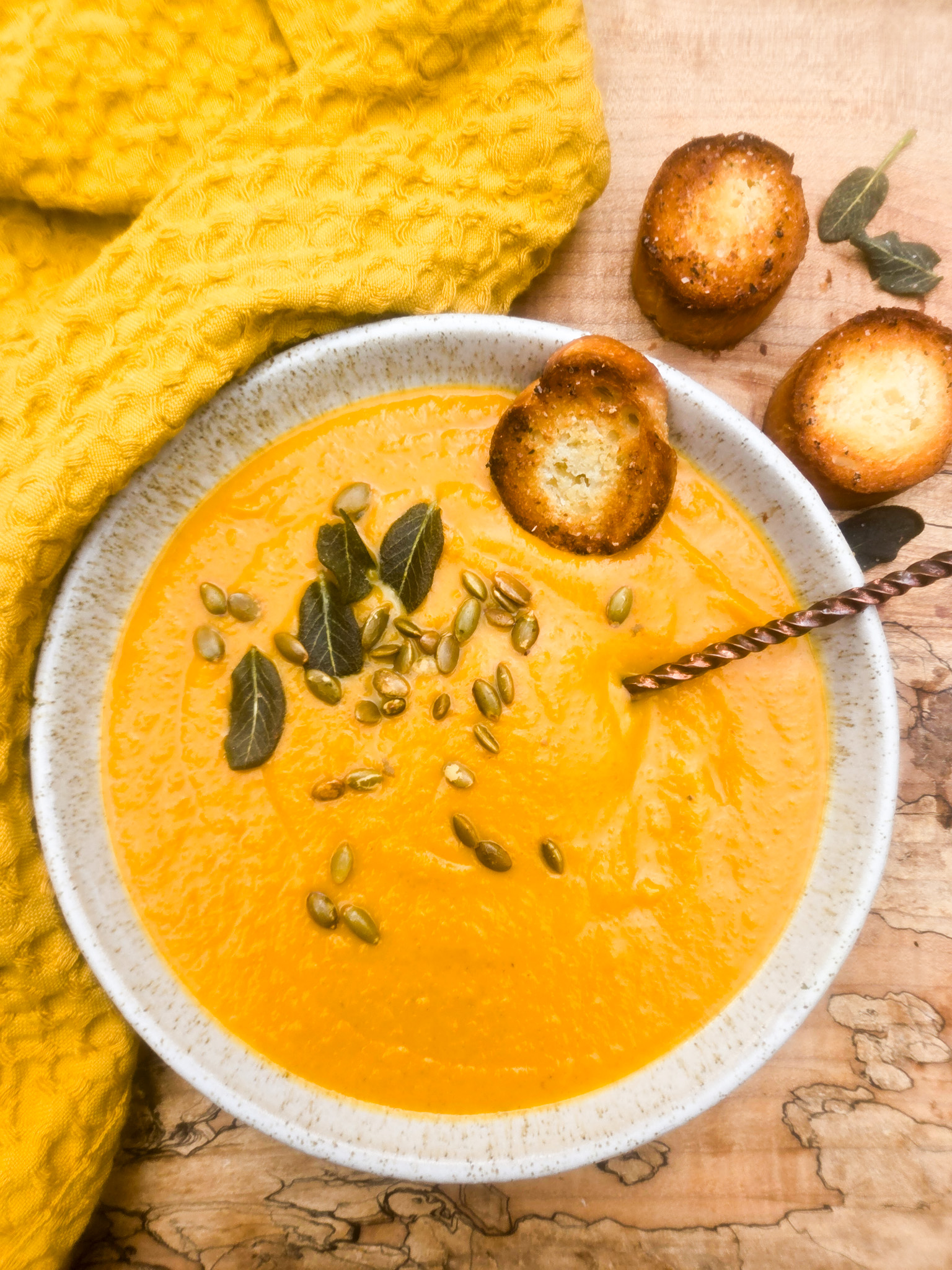 Acorn Squash Soup is warm and creamy with earthy spices like paprika, turmeric, cumin and chipotle, topped with fried sage and pepitas.