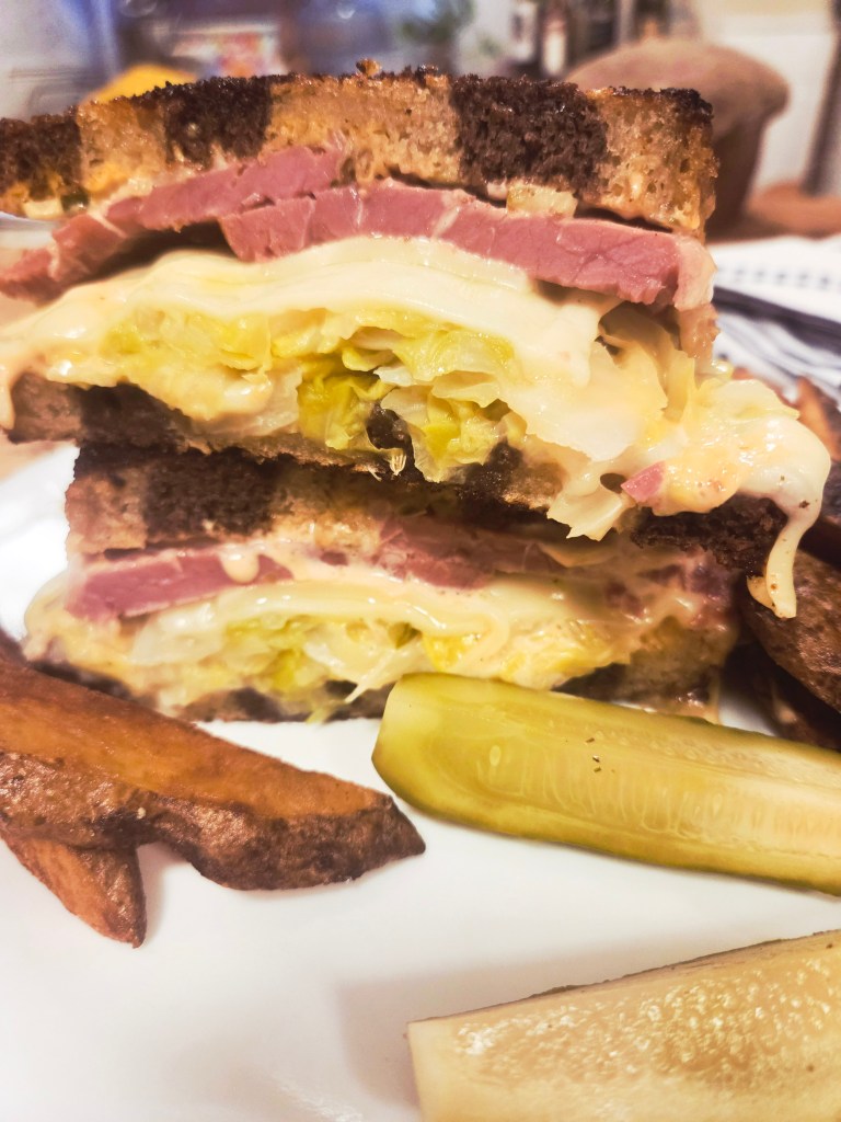 Reuben Sandwich layered with corned beef, sauerkraut, Swiss cheese and Russian dressing all on marbled sourdough rye bread