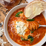Bowl of creamy stuffed shell soup with herbed ricotta on top