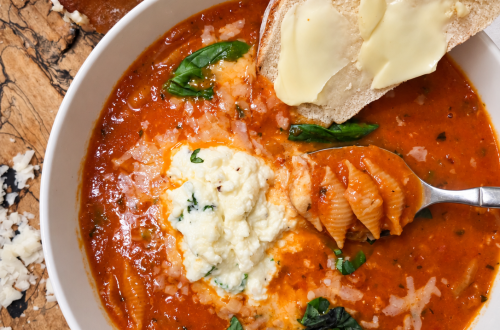 Bowl of creamy stuffed shell soup with herbed ricotta on top