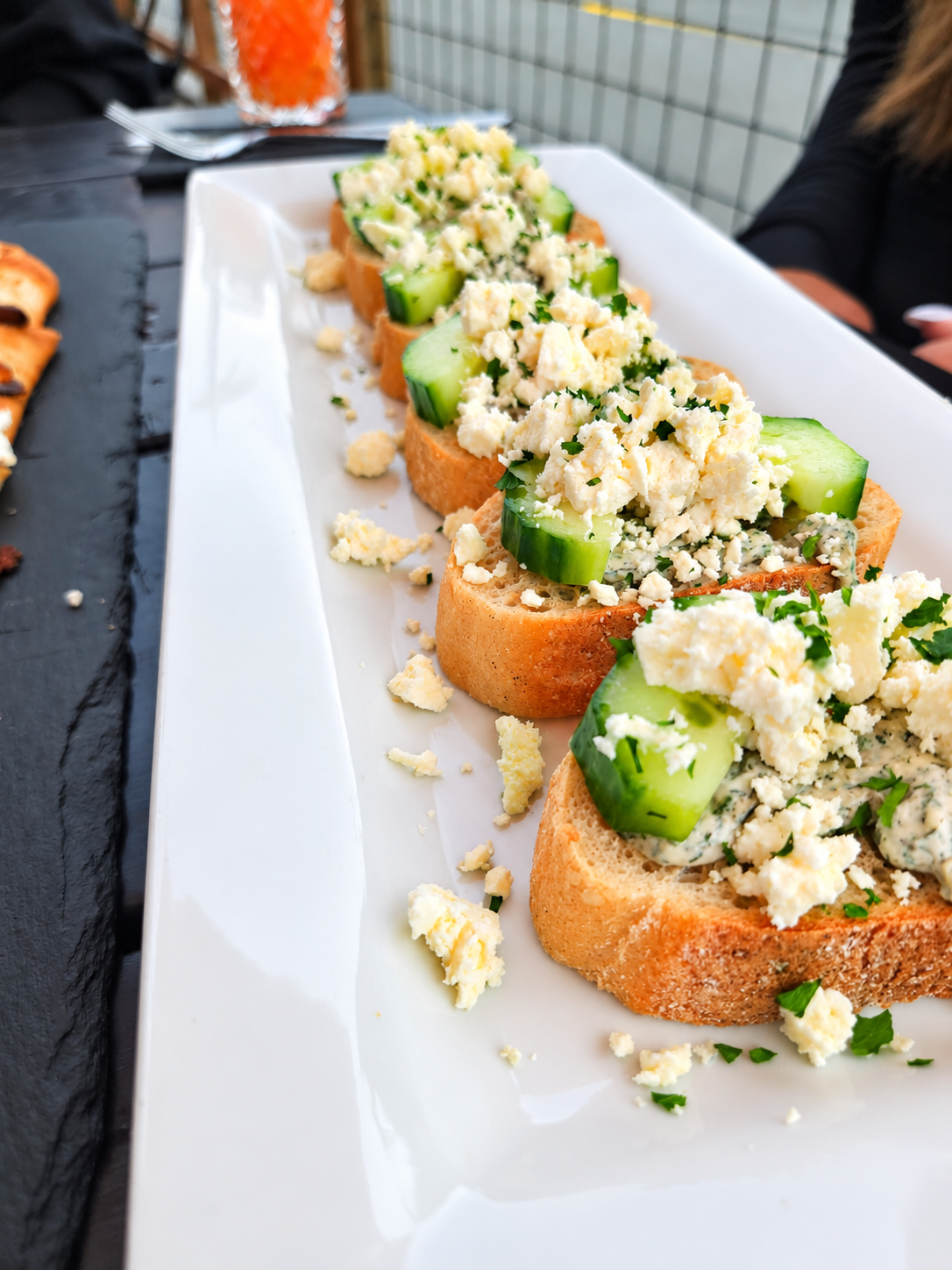 Cucumber bruschetta at The Lighthouse Bar & Restaurant with toasted rustic baguette, creamy dill spread, fresh cucumber slices, and crumbled feta cheese.