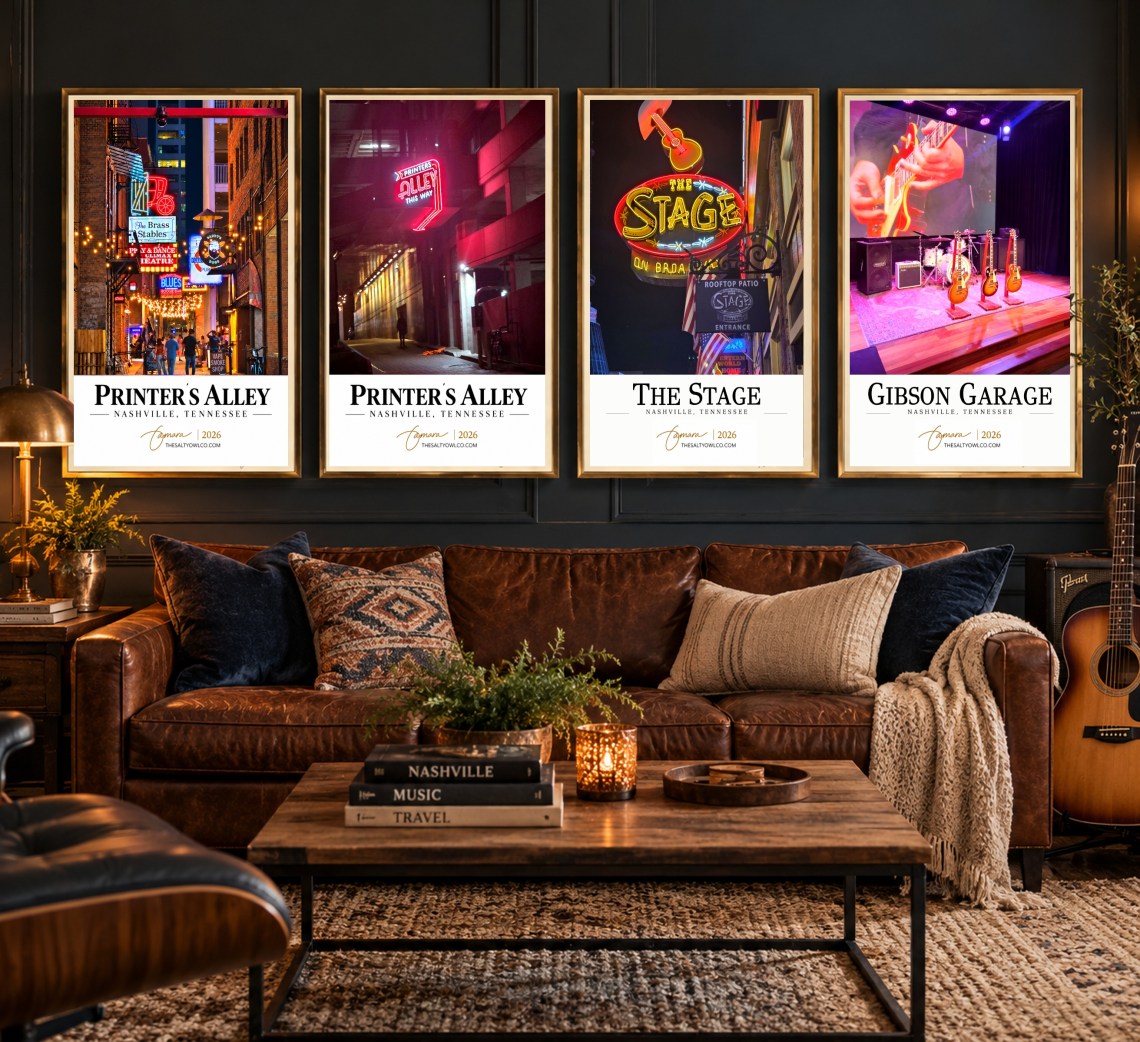 Four Nashville travel photography posters from The Salty Owl Travel Collection displayed in slim gold frames above a cognac leather sofa in a moody living room with charcoal walls, warm brass lighting, and music-inspired decor.
