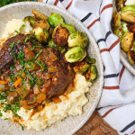 Italian pot roast with creamy polenta and roasted Brussels sprouts on a speckled plate.