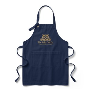 Dark navy blue apron featuring The Salty Owl Co. signature gold owl logo on the front, combining modern coastal style with everyday kitchen functionality.